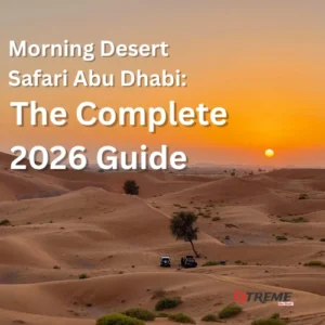 Two 4x4 vehicles crossing the golden sand dunes of Al Khatim Desert at sunrise during a morning desert safari in Abu Dhabi, with a warm amber sky and the sun low on the horizon.