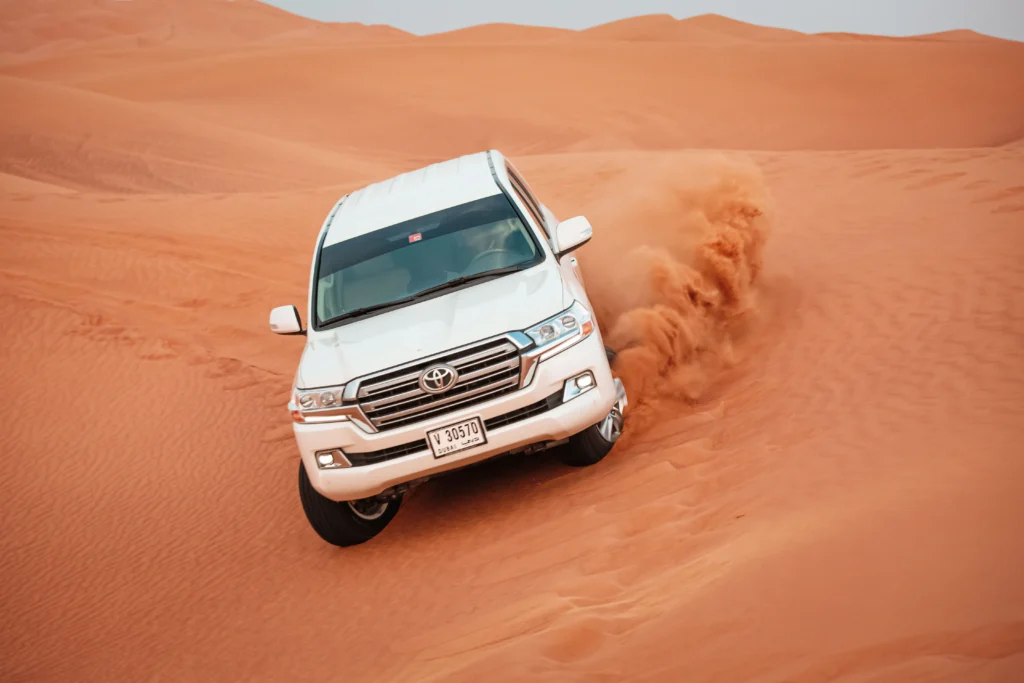 Toyota Land Cruiser cresting a steep dune face during a desert safari at Al Khatim Desert, Abu Dhabi