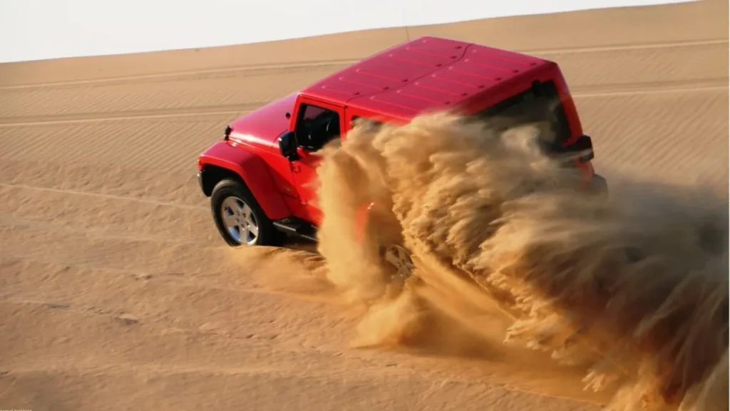 High-angle view of a Hummer driving through desert dunes during a desert safari adventure