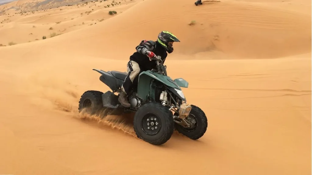 Tourist enjoying quad biking adventure on sand dunes during desert safari